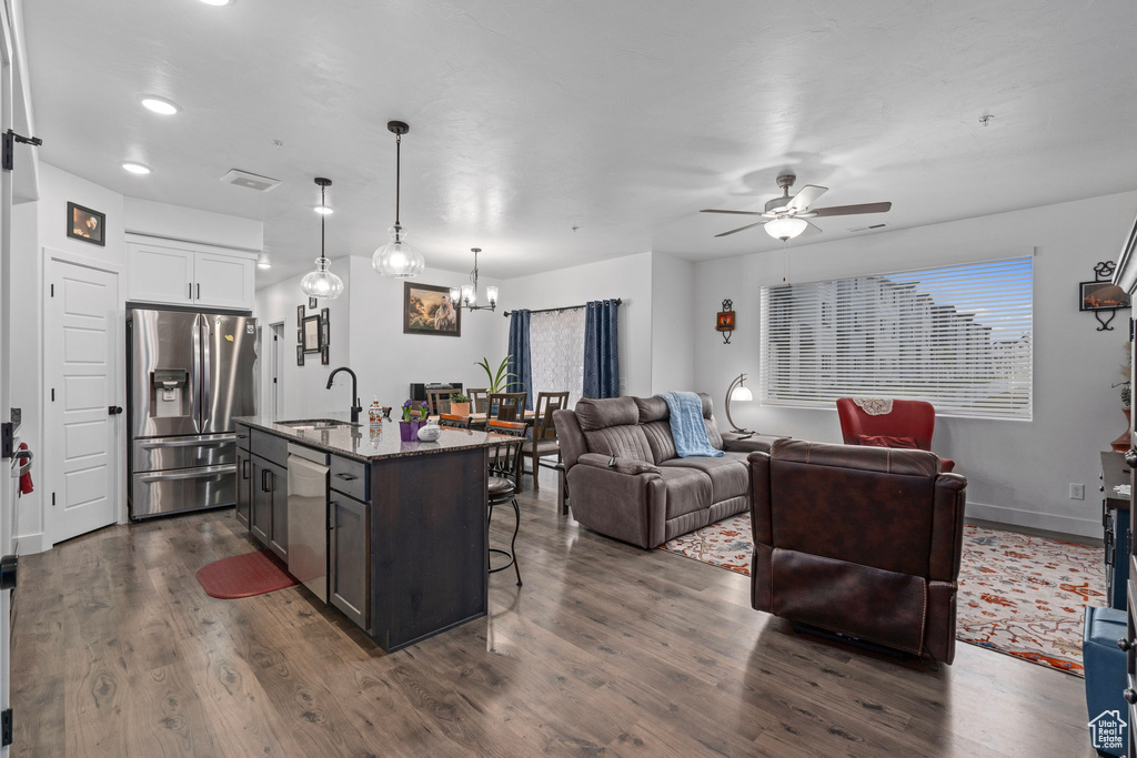 Kitchen with stainless steel appliances, a breakfast bar, a sink, open floor plan, and ceiling fan with notable chandelier