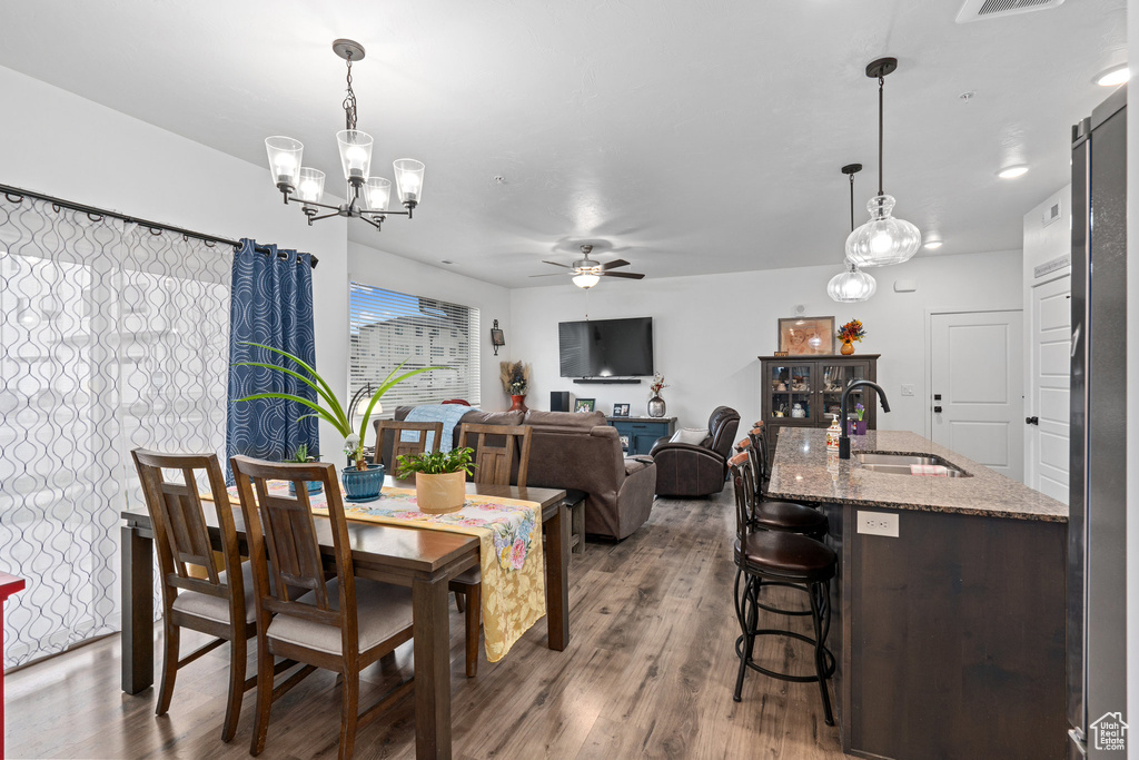 Dining space featuring ceiling fan with notable chandelier, wood finished floors, and visible vents