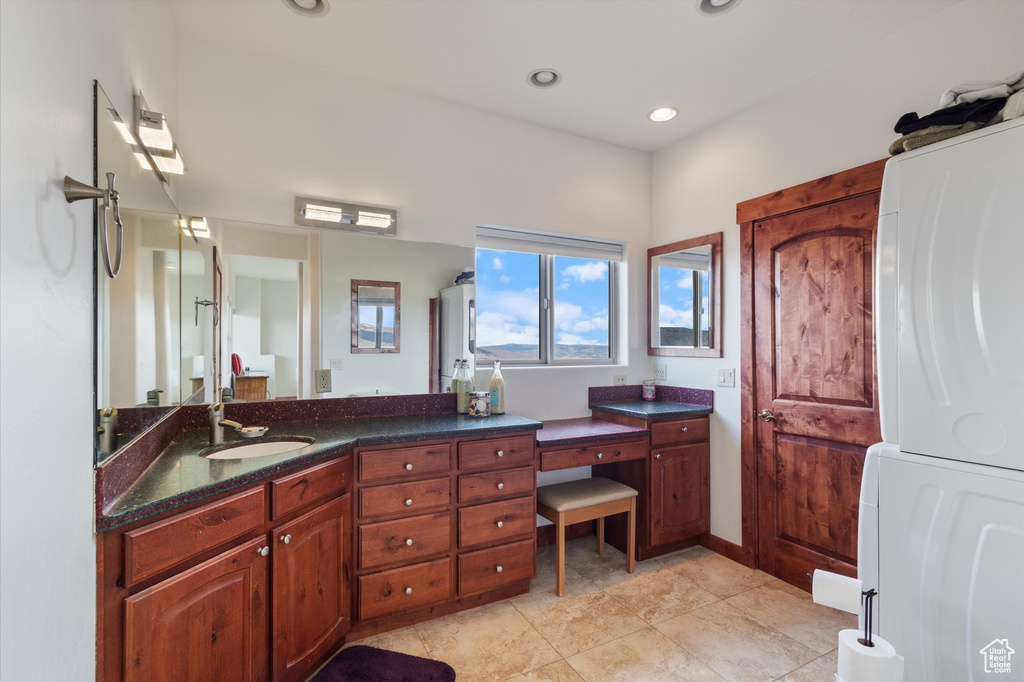 Bathroom featuring vanity, tile patterned flooring, stacked washer and clothes dryer, and recessed lighting