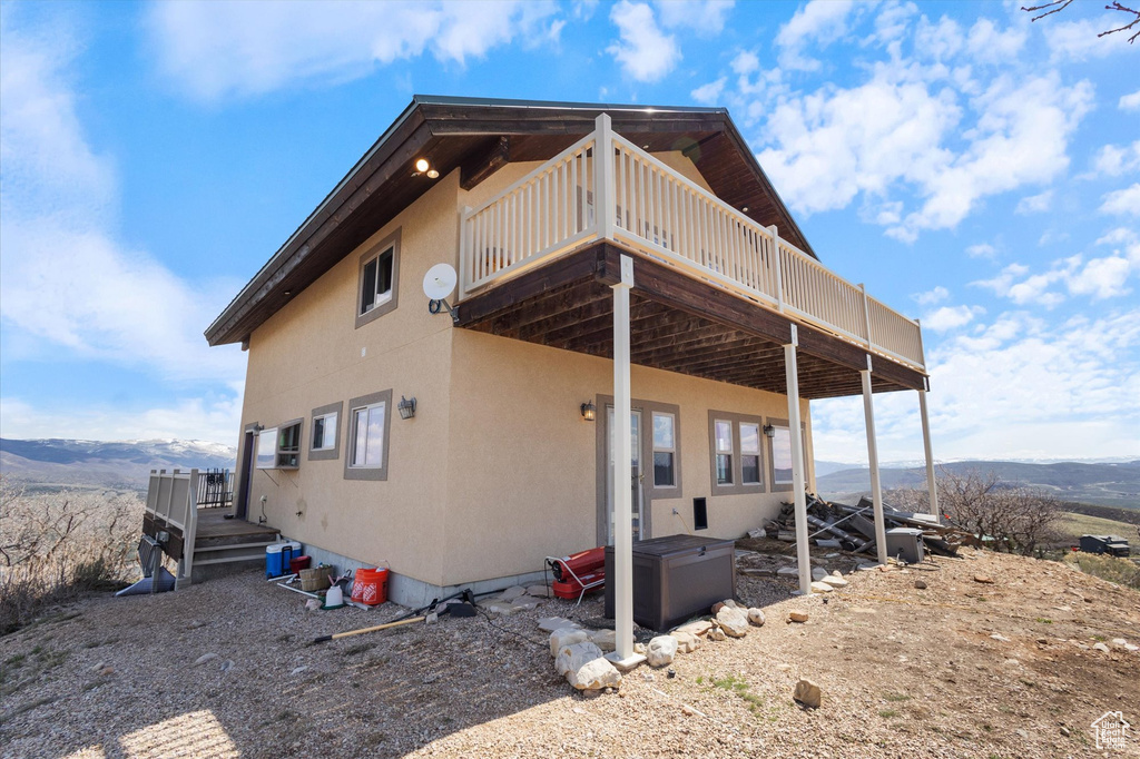 Rear view of house featuring a deck with mountain view and stucco siding