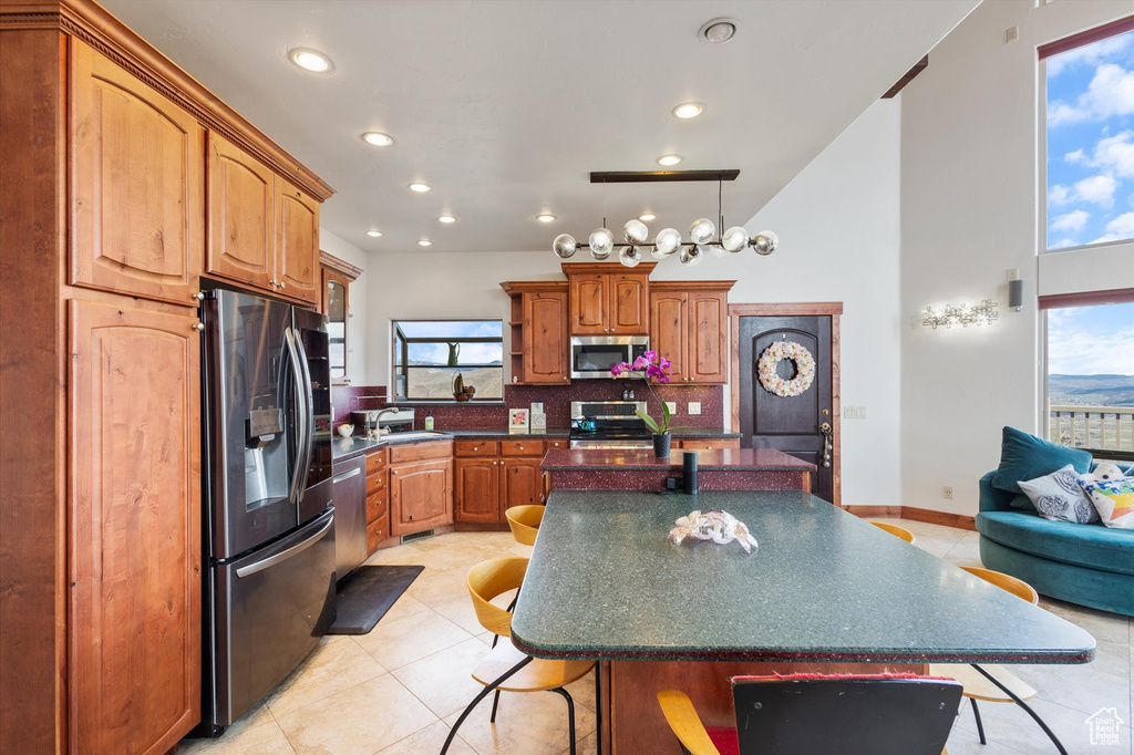 Kitchen featuring dark countertops, a sink, a breakfast bar, stainless steel appliances, and a kitchen island