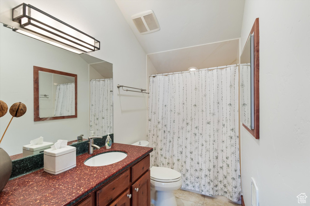 Bathroom with toilet, visible vents, lofted ceiling, tile patterned flooring, and vanity