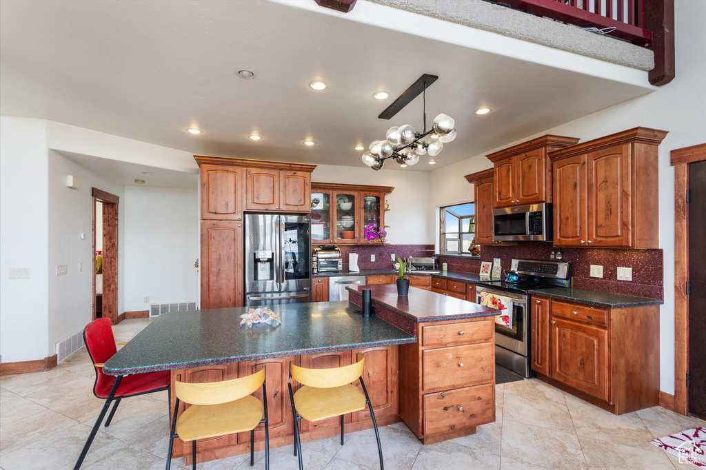 Kitchen with a kitchen bar, backsplash, appliances with stainless steel finishes, and a kitchen island