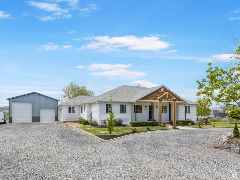 View of front of house featuring driveway, an outbuilding, covered porch, and a garage