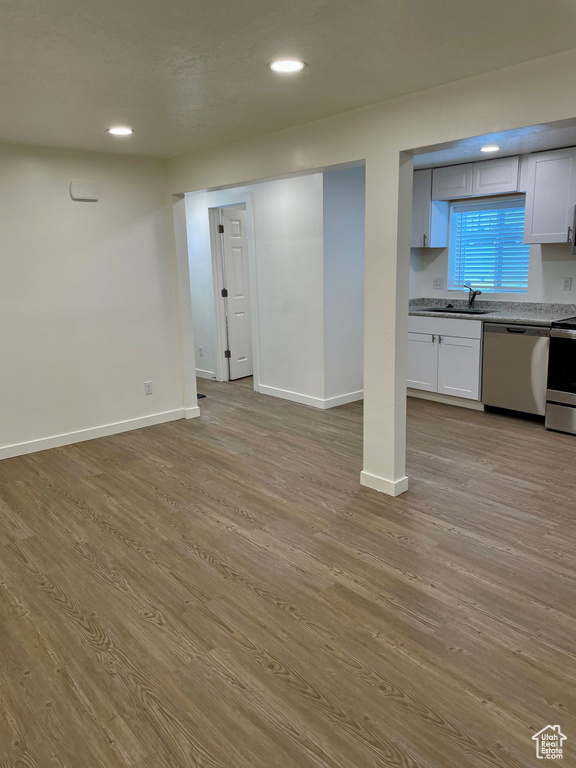 Below grade area with wood finished floors, baseboards, recessed lighting, and a sink