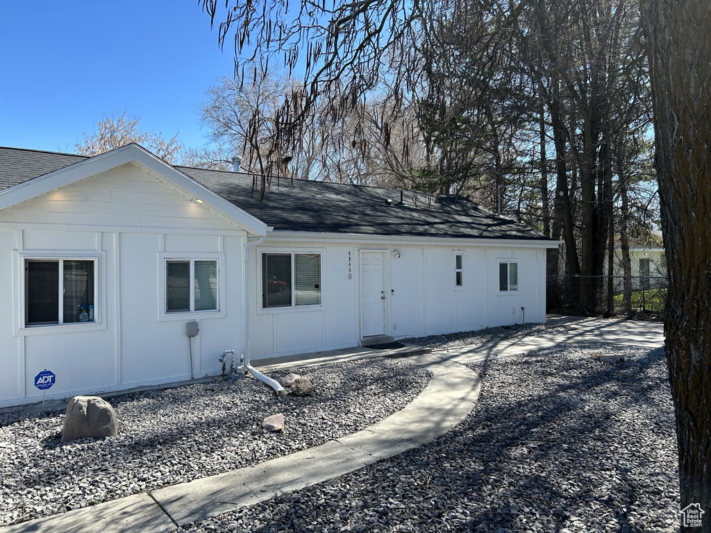 View of front facade featuring a shingled roof, fence, and board and batten siding
