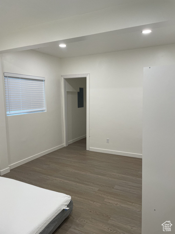 Unfurnished bedroom featuring dark wood-type flooring, baseboards, electric panel, and recessed lighting