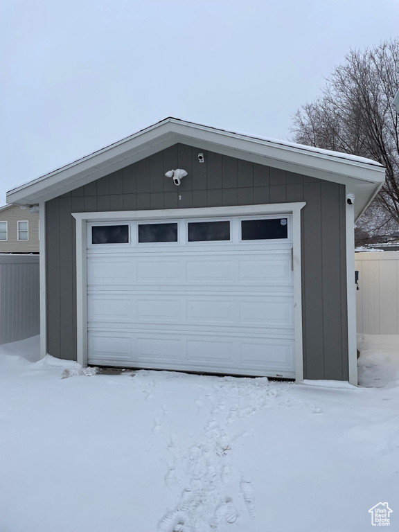 Snow covered garage with fence