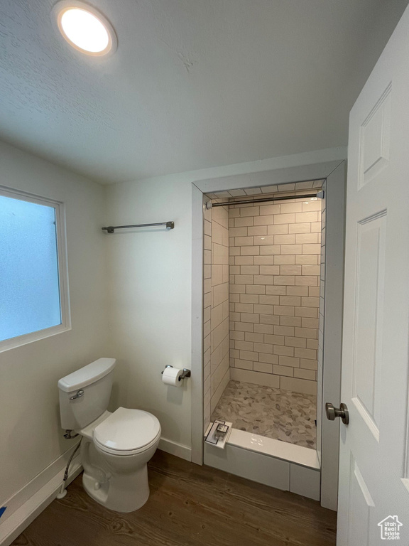Full bath featuring wood finished floors, toilet, a stall shower, and baseboards