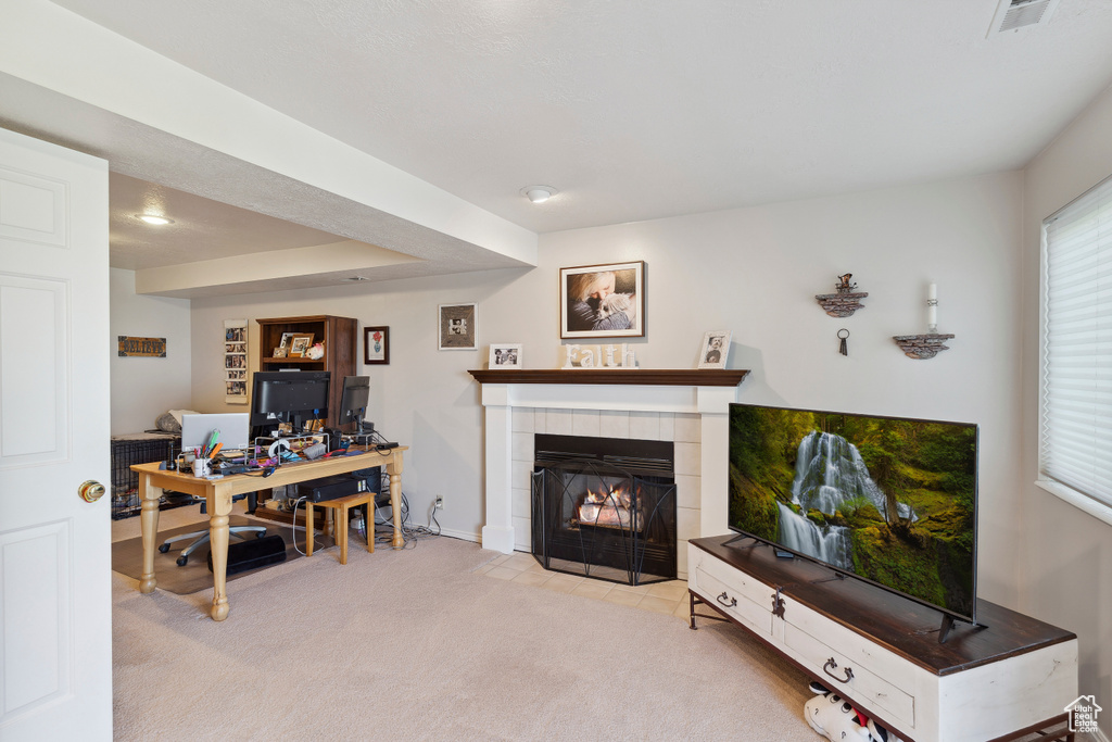 Carpeted living room featuring a tiled fireplace, baseboards, and visible vents