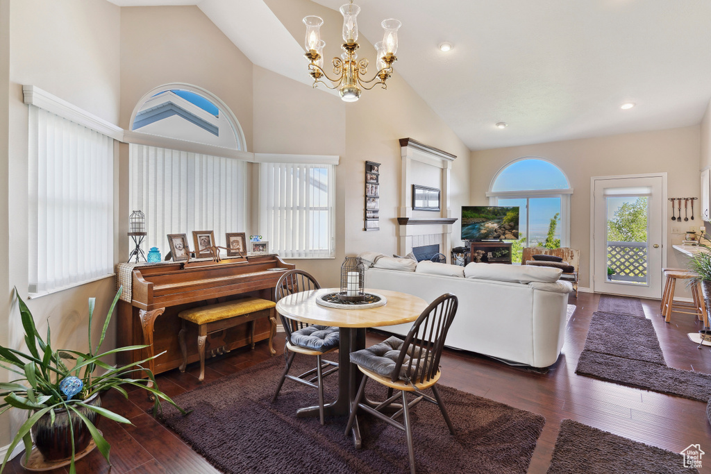 Dining space featuring a notable chandelier, a fireplace, high vaulted ceiling, recessed lighting, and wood finished floors
