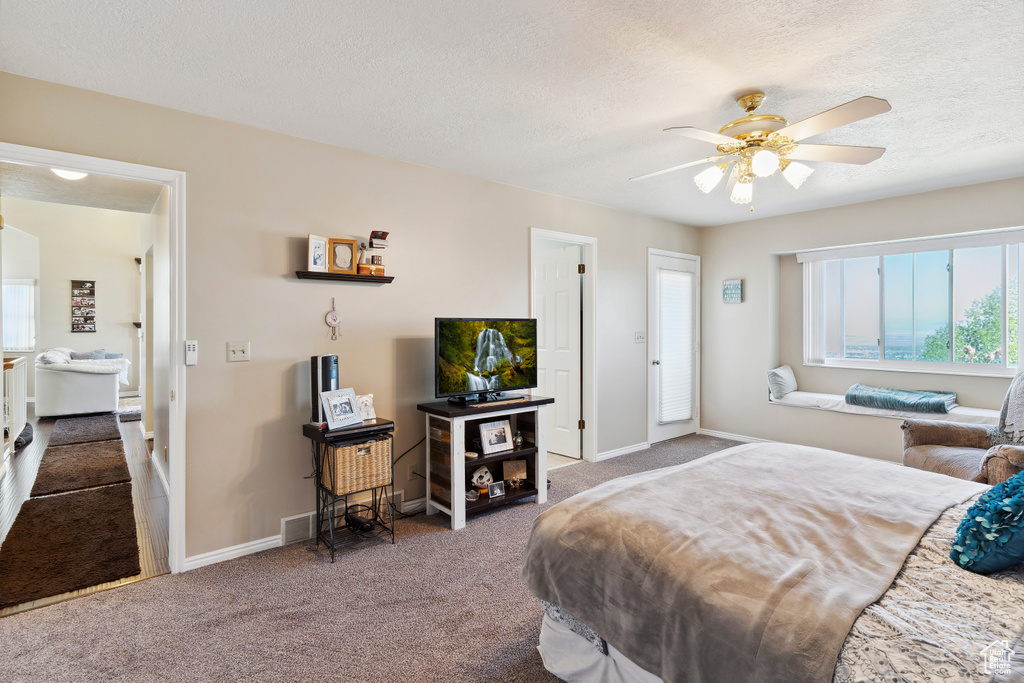 Carpeted bedroom featuring baseboards, ceiling fan, a textured ceiling, and visible vents
