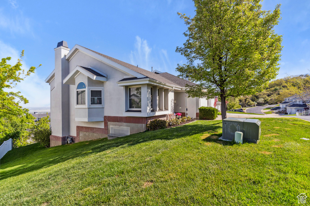 View of property exterior with a yard, a chimney, and stucco siding