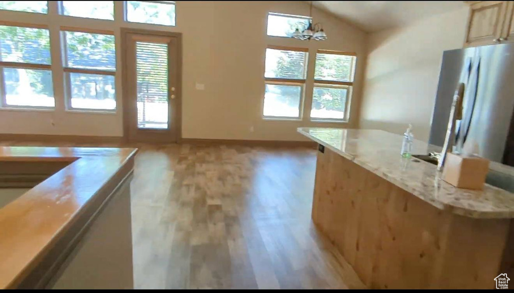 Kitchen featuring plenty of natural light, light wood finished floors, baseboards, and lofted ceiling