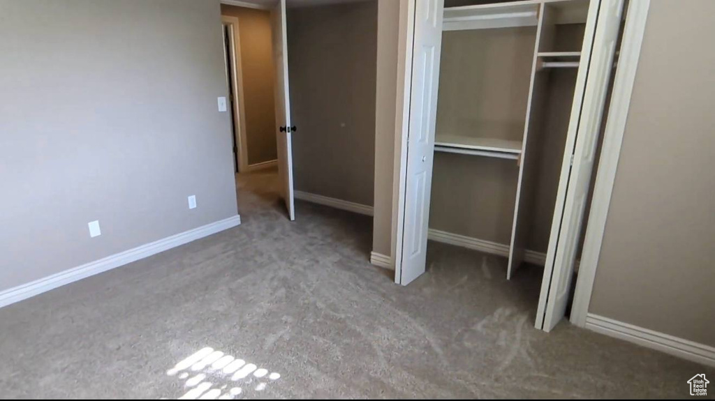 Unfurnished bedroom featuring carpet, a closet, and baseboards