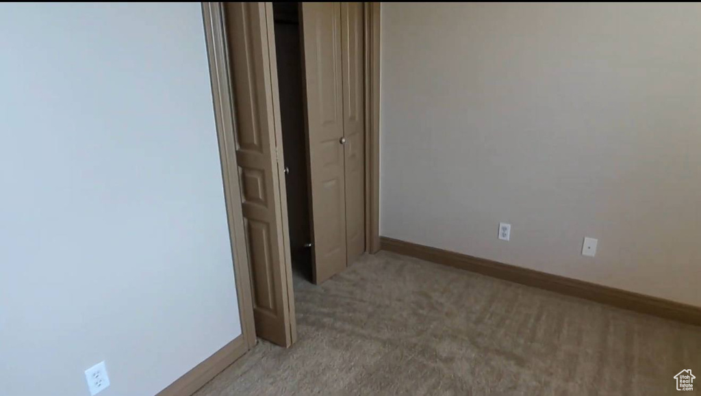 Empty room featuring light carpet and baseboards