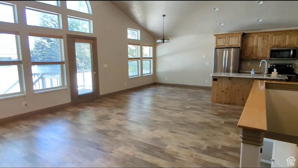 Kitchen with appliances with stainless steel finishes, light wood-style floors, baseboards, a sink, and light countertops