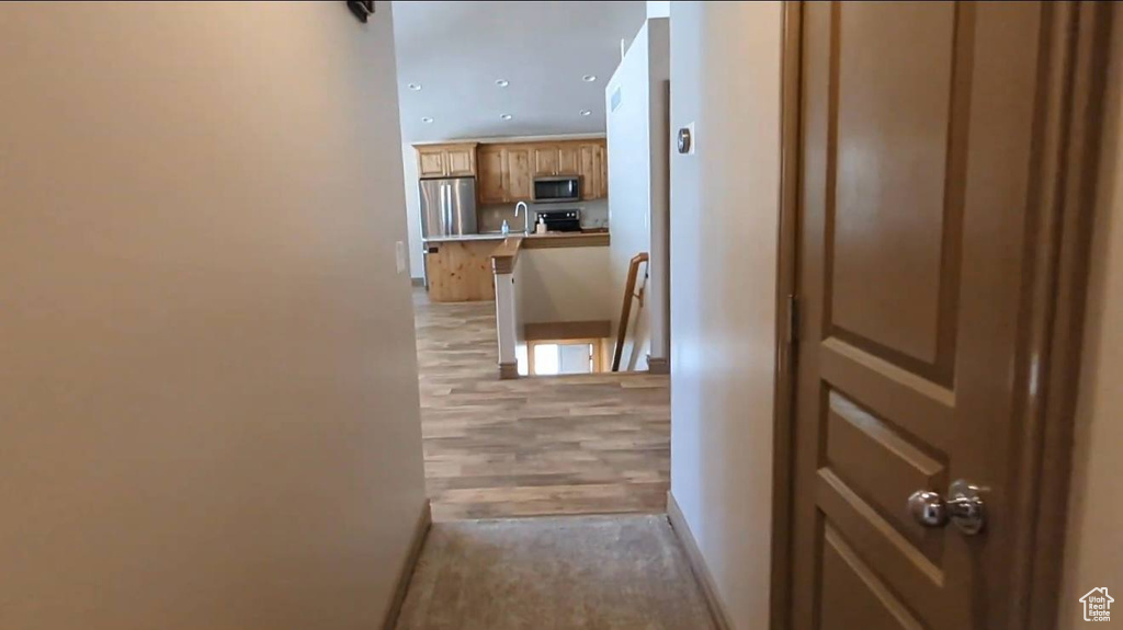 Hall featuring an upstairs landing, a sink, baseboards, and recessed lighting