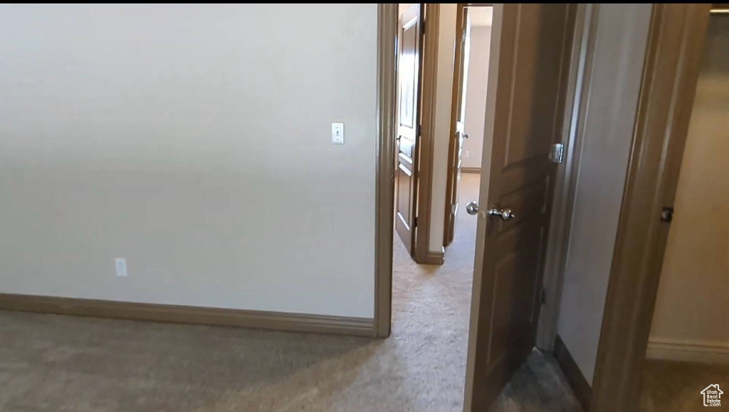 Hallway with baseboards and carpet