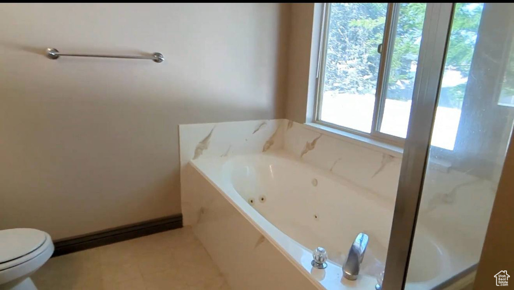 Bathroom featuring a whirlpool tub, toilet, and tile patterned floors