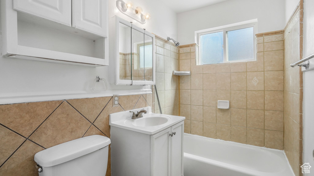 Full bathroom featuring tile walls, bathing tub / shower combination, vanity, and toilet