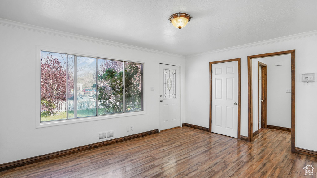 Unfurnished bedroom featuring wood finished floors, visible vents, crown molding, and multiple windows