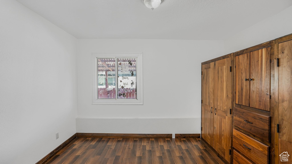 Unfurnished bedroom featuring baseboards and dark wood finished floors