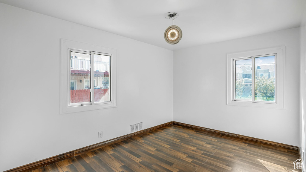 Spare room featuring baseboards, visible vents, and dark wood-style floors