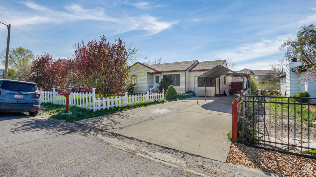 View of front facade with a carport, concrete driveway, and a fenced front yard