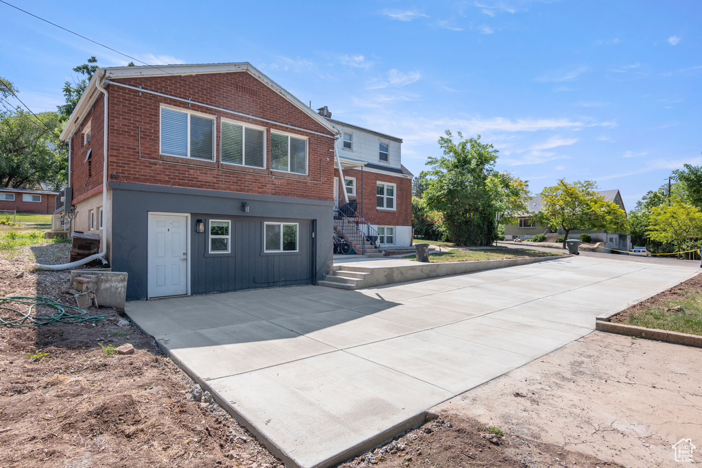 Rear view of property with brick siding, stairs, and a patio