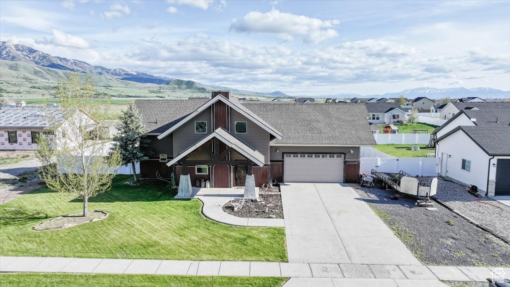 View of front of property featuring driveway, a garage, a residential view, and a mountain view