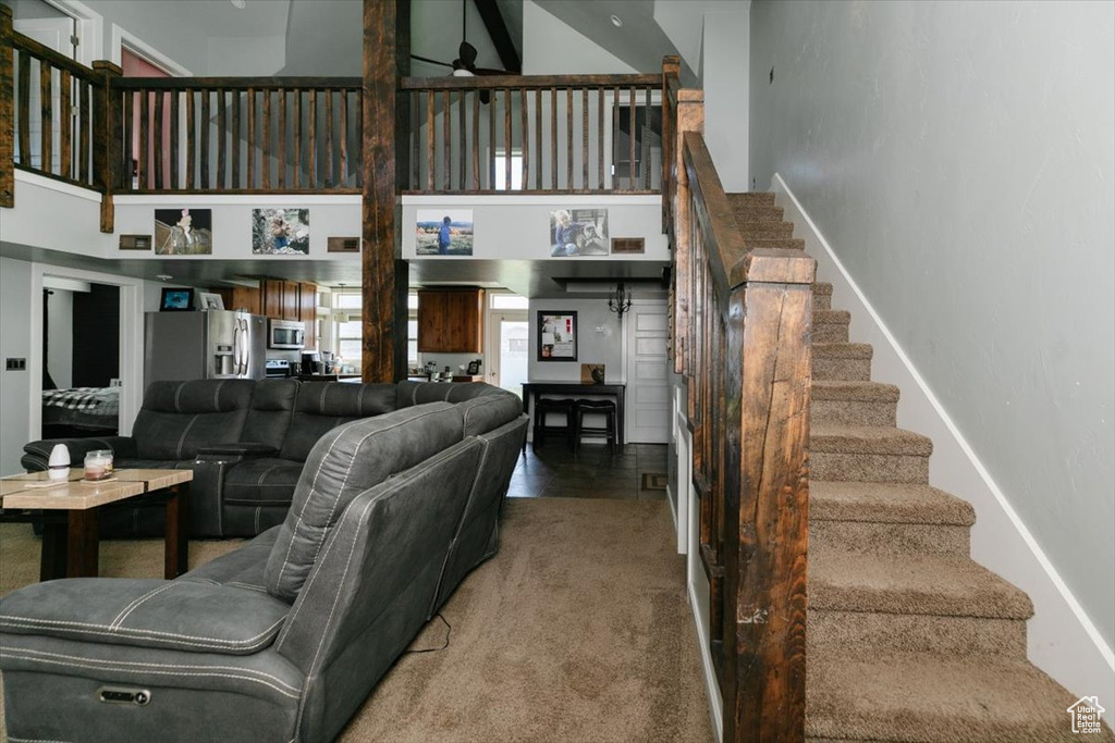 Living area with stairs, a ceiling fan, baseboards, and a towering ceiling