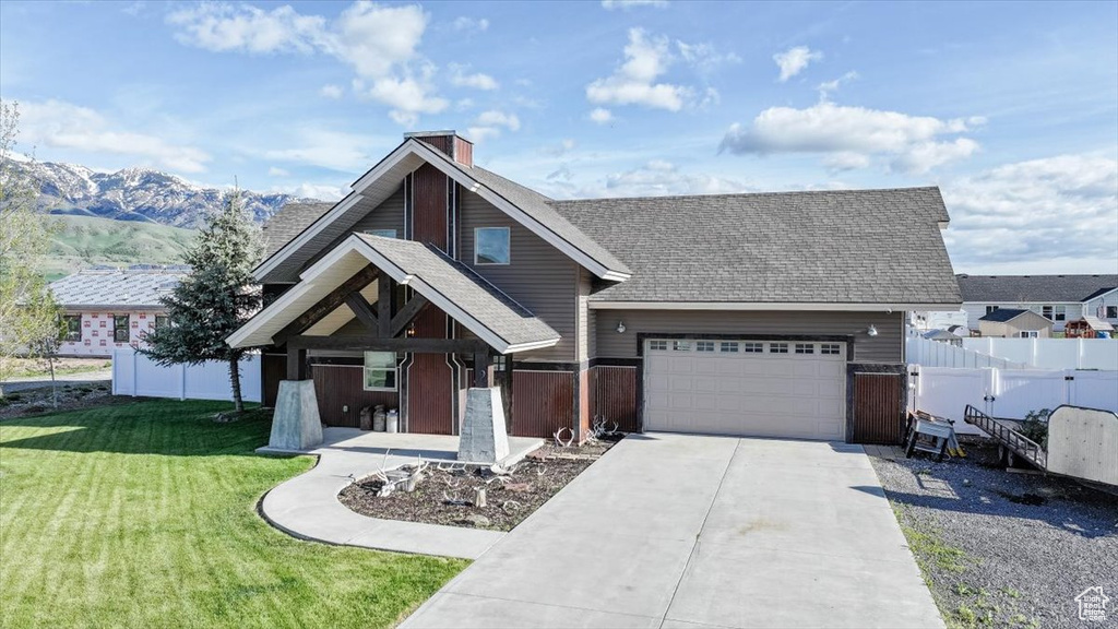 View of front of property featuring driveway, a garage, roof with shingles, a mountain view, and a chimney