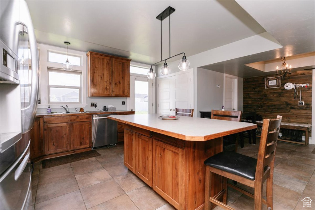 Kitchen featuring dishwasher, brown cabinets, a kitchen bar, a kitchen island, and healthy amount of natural light