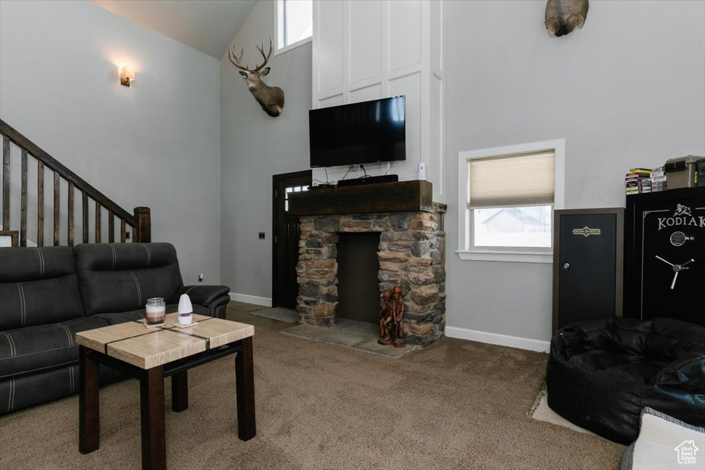 Carpeted living area featuring high vaulted ceiling, stairway, and baseboards