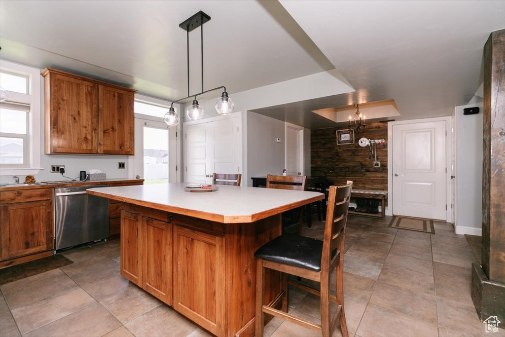 Kitchen featuring dishwasher, brown cabinetry, a breakfast bar, and a kitchen island