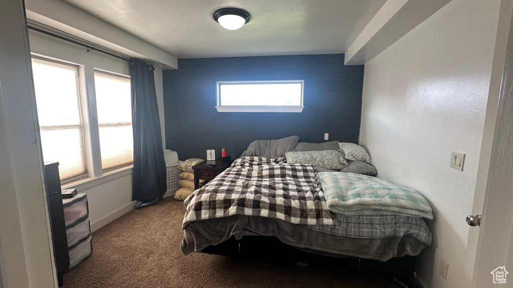 Bedroom with an accent wall, wood walls, and carpet flooring