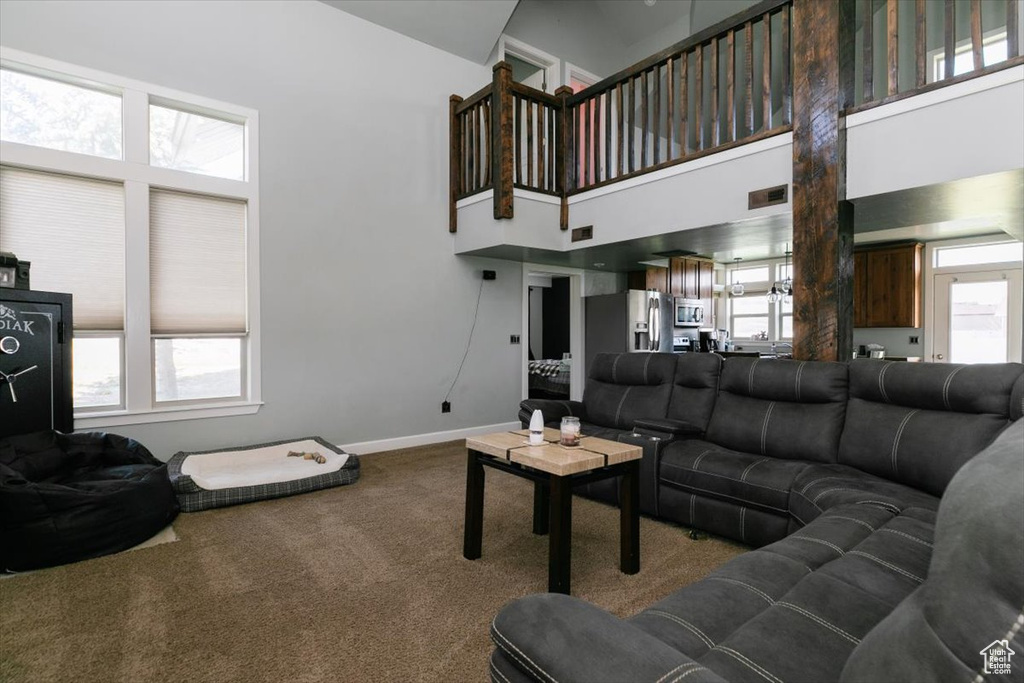 Living area with carpet, high vaulted ceiling, and baseboards