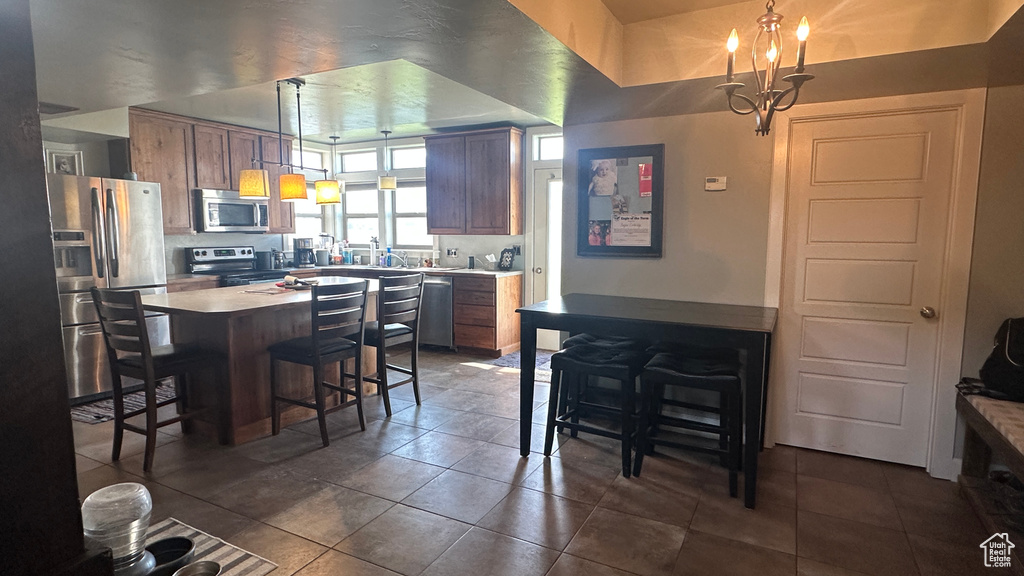 Kitchen with a chandelier, stainless steel appliances, a center island, a breakfast bar area, and pendant lighting