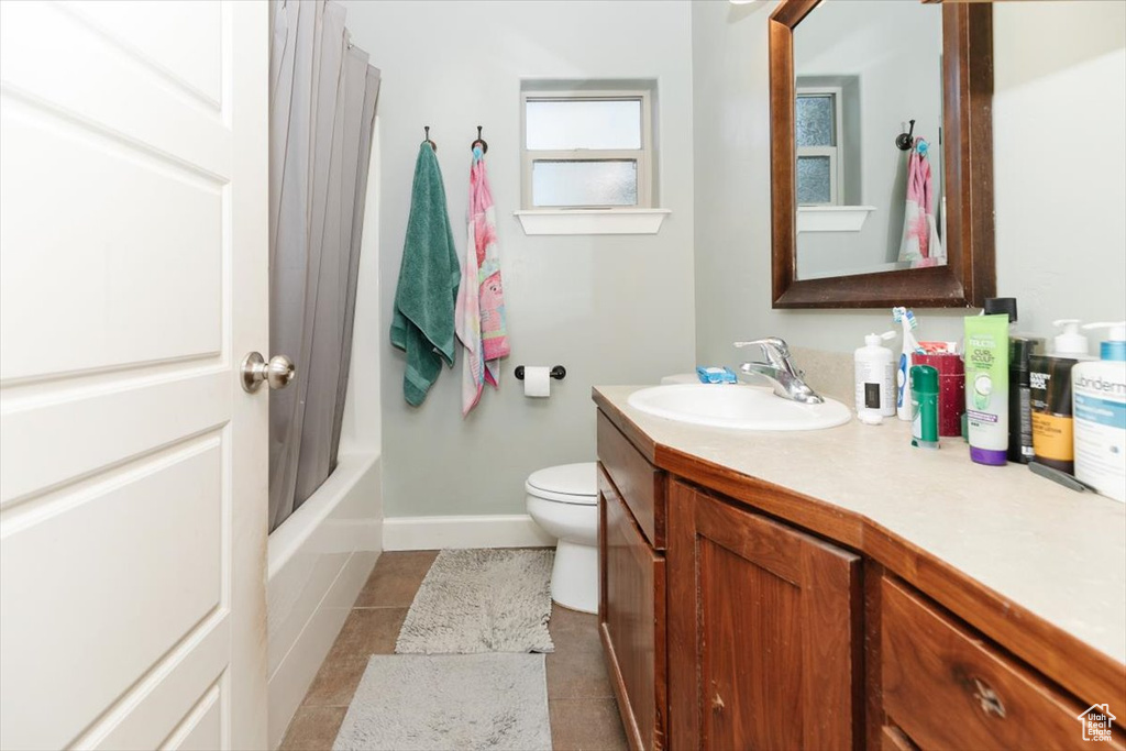 Bathroom featuring vanity, tile patterned floors, toilet, baseboards, and shower / bathtub combination with curtain