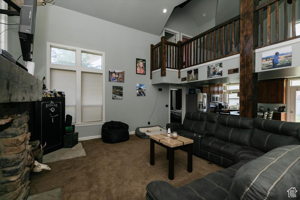Carpeted living area with high vaulted ceiling and baseboards