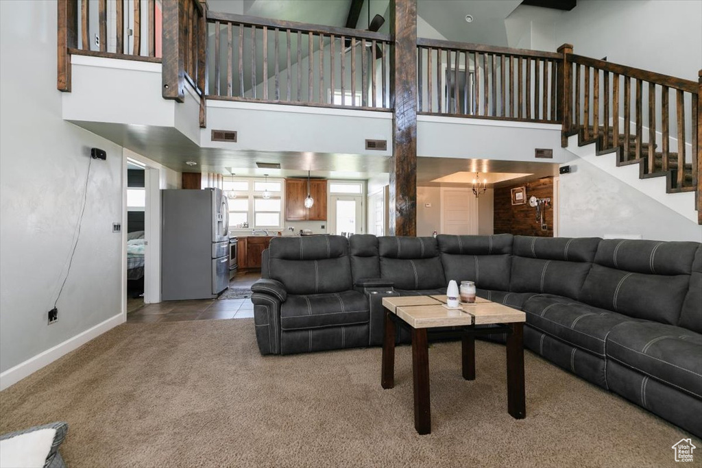 Living room with a high ceiling, carpet floors, baseboards, and stairway
