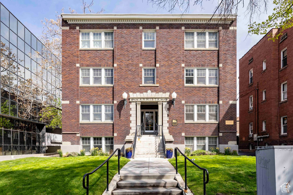 View of front of property featuring a front lawn and brick siding