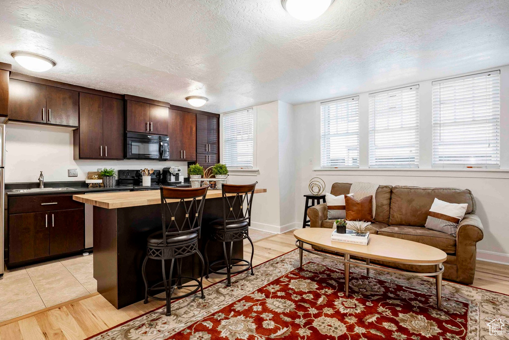 Kitchen with a textured ceiling, a kitchen breakfast bar, and black appliances