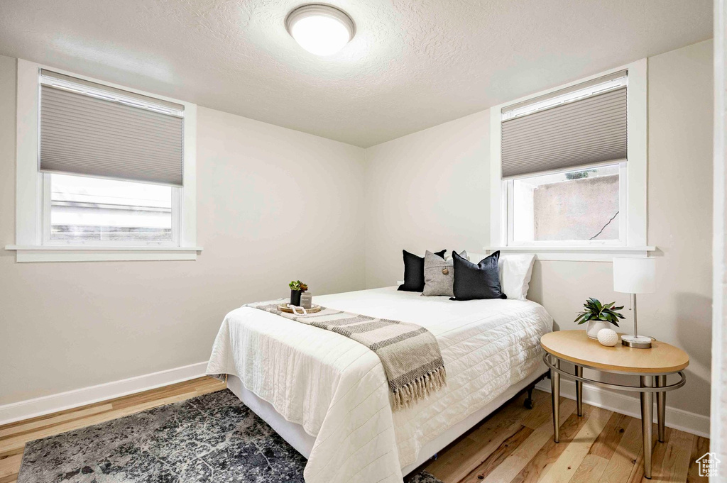 Bedroom featuring baseboards, multiple windows, and light wood-type flooring