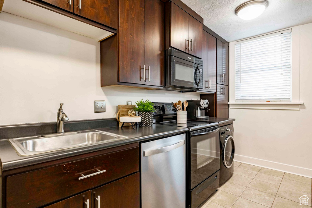 Kitchen featuring a sink, light tile patterned flooring, black appliances, a textured ceiling, and washer / clothes dryer