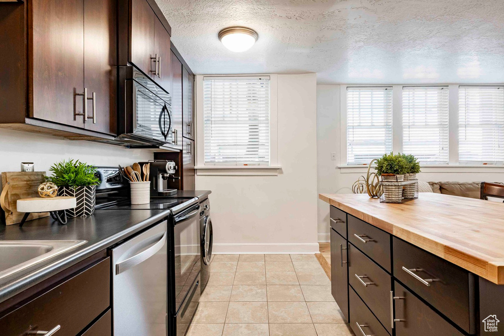 Kitchen with stainless steel dishwasher, black microwave, range with electric stovetop, butcher block counters, and baseboards