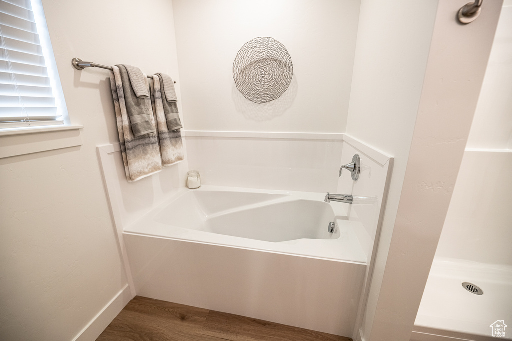 Bathroom featuring wood finished floors and a garden tub