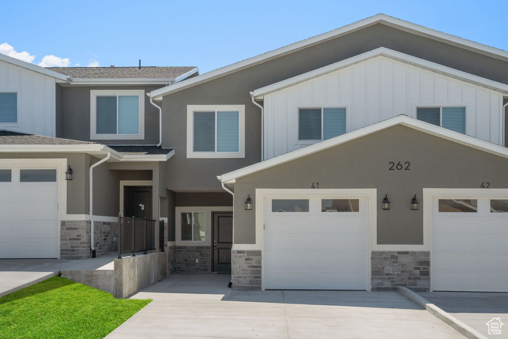 View of front of home featuring driveway, stone siding, and board and batten siding