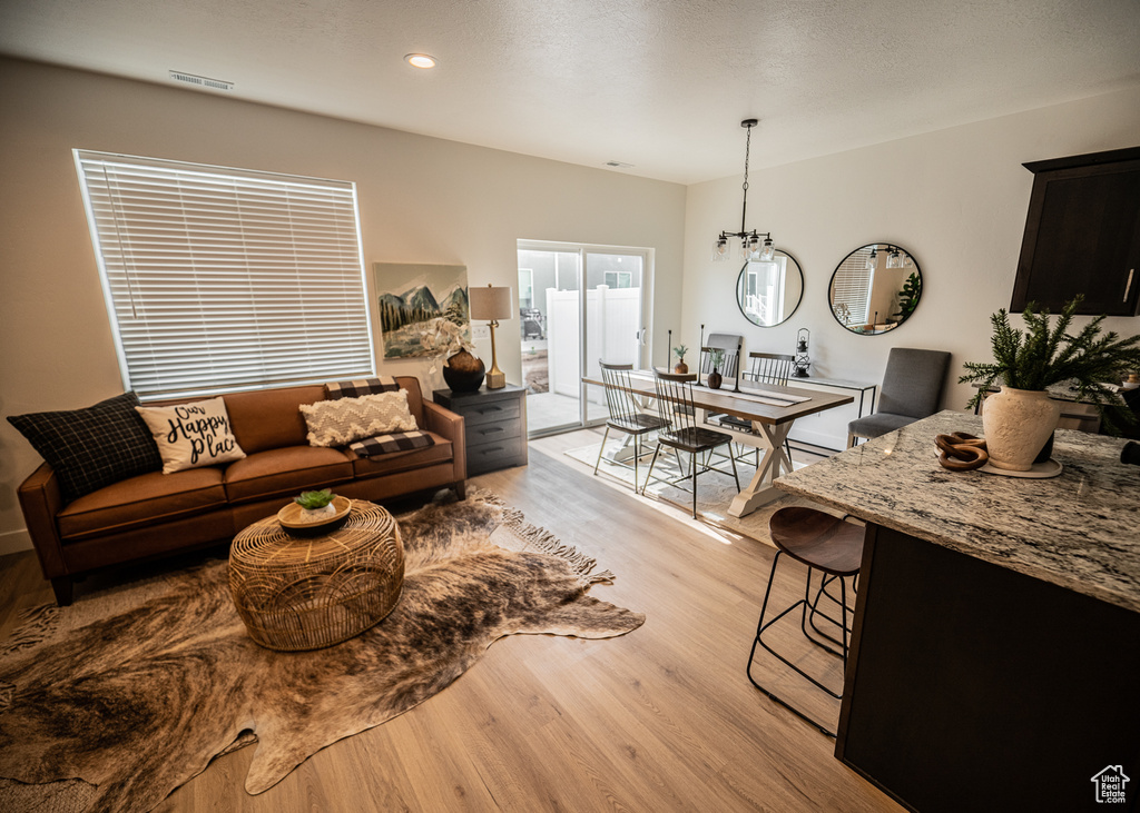 Living room featuring recessed lighting, a notable chandelier, visible vents, and light wood-style flooring